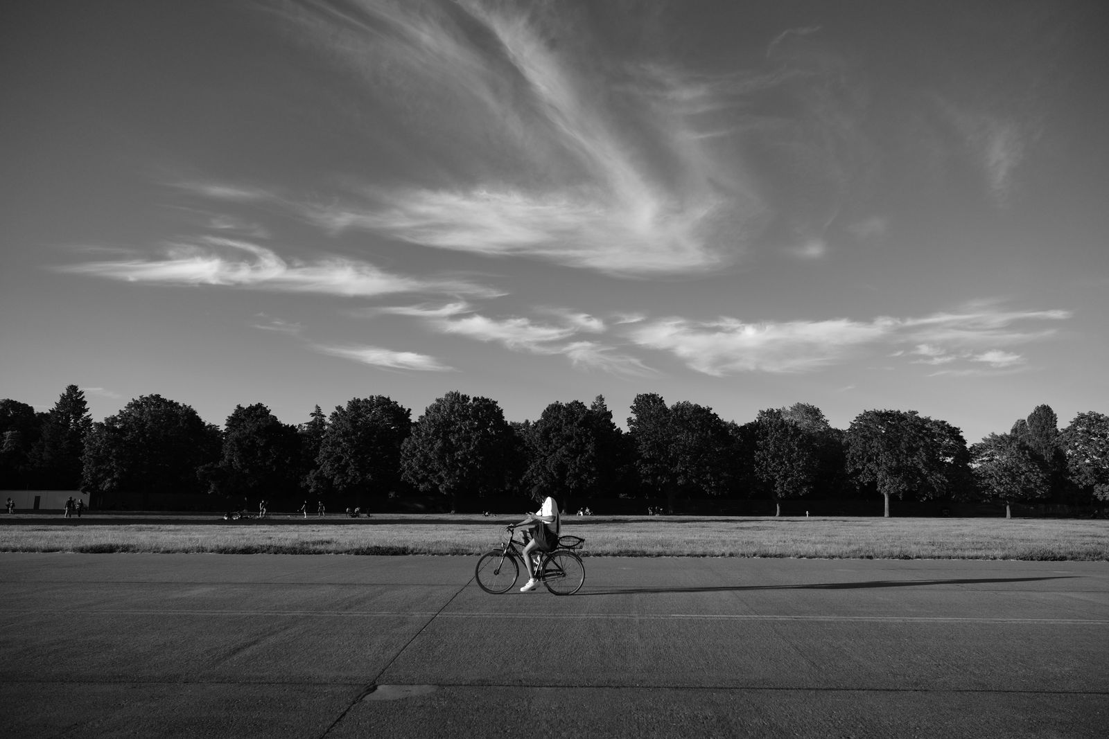 A cyclist crosses the old airfield at Tempelhof, Berlin, under a streaked evening sky